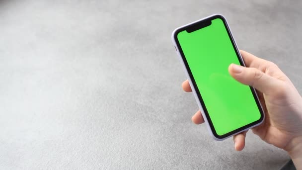 男人用绿色的屏幕触摸和看智能手机的屏幕 手机屏幕上的铬键在商人手中 背景是灰色的 — 图库视频影像