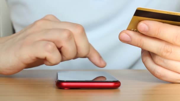 男はクレジットカードでオンラインショッピング スマートフォンでオンラインバンキング 男は銀行カード番号を入力します 手を閉じろ ライフスタイル技術と電子商取引の概念 — ストック動画