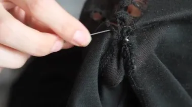 Kadın siyah pantolona delikler dikiyor. El yapımı dikiş. Yoksulluk ve dilencilik kavramı. 
