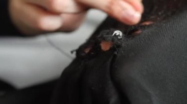 Kadın siyah pantolona delikler dikiyor. El yapımı dikiş. Yoksulluk ve dilencilik kavramı. 