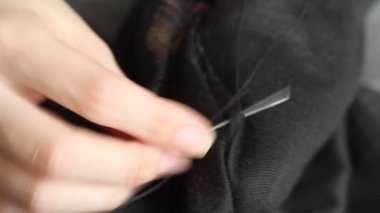 Kadın siyah pantolona delikler dikiyor. El yapımı dikiş. Yoksulluk ve dilencilik kavramı. 