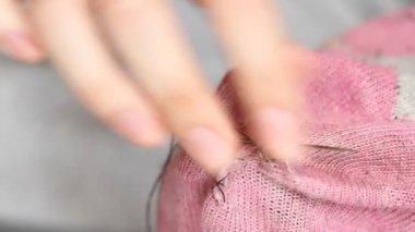 Kadın pembe çoraplarda delikler açıyor. El yapımı dikiş. Yoksulluk ve dilencilik kavramı. 