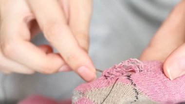 Kadın pembe çoraplarda delikler açıyor. El yapımı dikiş. Yoksulluk ve dilencilik kavramı. 