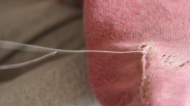 Kadın pembe çoraplarda delikler açıyor. El yapımı dikiş. Yoksulluk ve dilencilik kavramı. 