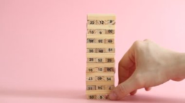 Kadın ve erkek pembe arka planda jenga oynuyorlar. Aile eğlencesi ve tatil konsepti.