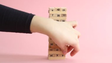 Kadın ve erkek pembe arka planda jenga oynuyorlar. Aile eğlencesi ve tatil konsepti.