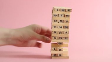 Kadın ve erkek pembe arka planda jenga oynuyorlar. Aile eğlencesi ve tatil konsepti.