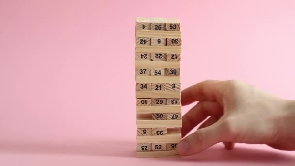 Frau und Mann spielen Jenga auf rosa Hintergrund. Familienfreizeit- und Urlaubskonzept. — Stockvideo