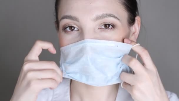 女性は ウイルス感染予防と保護のための医療面のマスクを置く — ストック動画