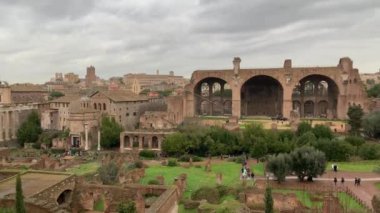 Roma, İtalya 28 Ocak 2020 'de kurulmuş. Antik Roma Forumu 'nu harabeye çevirdi. Turistler yağmurlu bir günde İtalya 'nın merkezindeki Roma forumunda yürürler. Tarihsel Avrupa mimarisi.