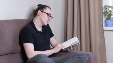 Koruyucu maskeli genç adam kitap okuyor. Koronavirüs salgını. Kendini karantinaya almak için evde kal.
