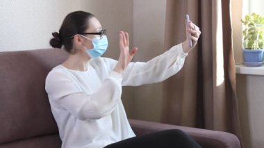 Koruyucu yüz maskesi takan genç kadın blogcu cep telefonuyla video kaydediyor. Koronavirüs salgını hakkında yayın yapan bir kadın blog yazarı. Kendini karantinaya almak için evde kal.