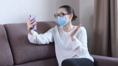 Koruyucu yüz maskesi takan genç kadın blogcu cep telefonuyla video kaydediyor. Koronavirüs salgını hakkında yayın yapan bir kadın blog yazarı. Kendini karantinaya almak için evde kal.