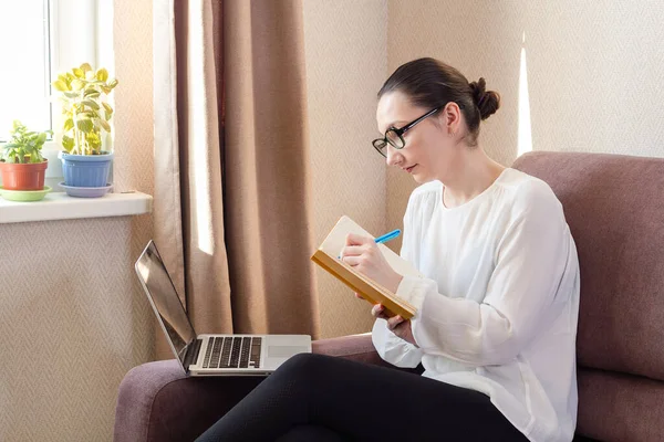 Młoda Kobieta Słucha Lekcji Online Lub Webinarium Pisze Notatki Pandemia — Zdjęcie stockowe