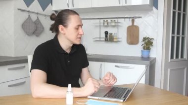 Genç blogcu koruyucu yüz maskesi takıyor ve laptop 'un webcam' ine video kaydediyor. Erkek blogcu internetten ders veriyor ya da virüsün yayılmasını önlemek için maske ve dezenfektan kullanıyor. Kendini karantina altına al