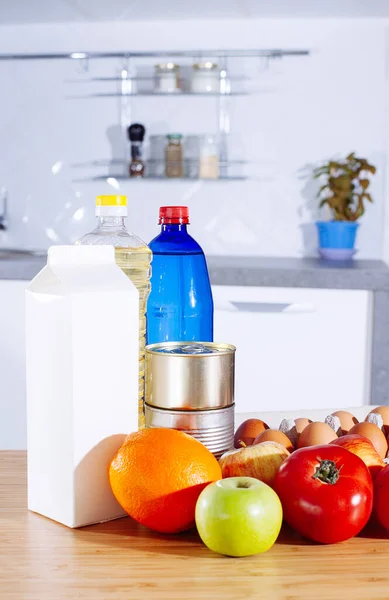 Set of fresh raw vegetables tomato, cucumber, egg, orange, apple, bottle of water and oil, milk on a wood table in a modern kitchen room. Healthy Eating. Organic food and products delivery