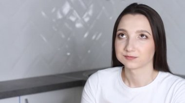 Genç esmer kadın beyaz mutfakta yemek çubuklarıyla suşi yiyor. Evde Japon yemeği, karantinada yiyecek teslimatı.