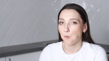 Genç esmer kadın beyaz mutfakta yemek çubuklarıyla suşi yiyor. Evde Japon yemeği, karantinada yiyecek teslimatı.