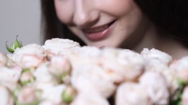 白人女人喜欢她的花束 年轻的黑发女子嗅到了白玫瑰的芬芳和微笑 走近了视野 — 图库视频影像