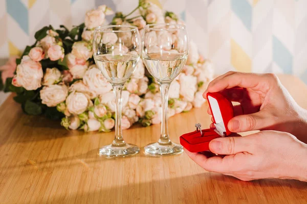 Closeup shot of marriage proposal. Man gives ring with diamond to woman proposing marriage. Indoors restaurant or home, romantic dinner