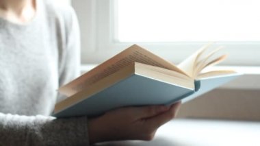 Oturma odasında kitap okuyan, sayfayı çeviren, öğrenen, eğitim alan, kitap okuyan, evde kalan genç bir kadın..