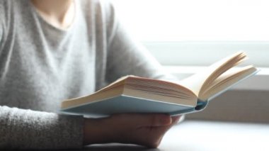 Oturma odasında kitap okuyan, sayfayı çeviren, öğrenen, eğitim alan, kitap okuyan, evde kalan genç bir kadın..