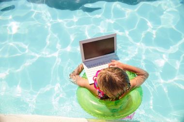 Havuz içinde laptop ile halka üzerinde yüzen küçük kız