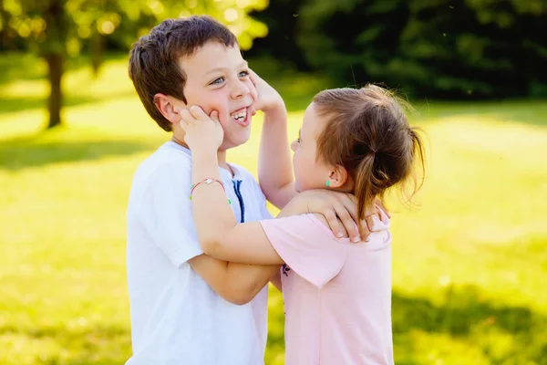 Cattivo bambina pizzicando guance di suo fratello — Foto Stock