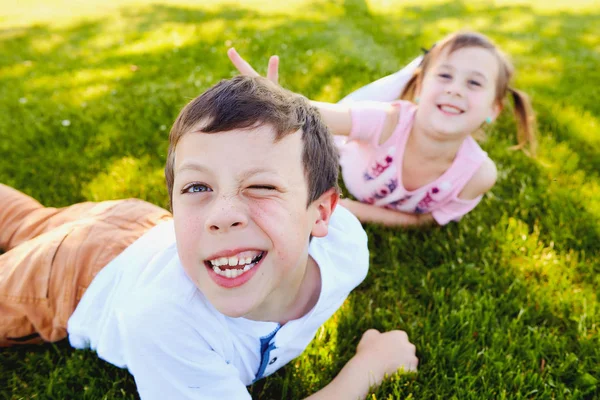 草の上に横たわるとからかって陽気な子供たち — ストック写真