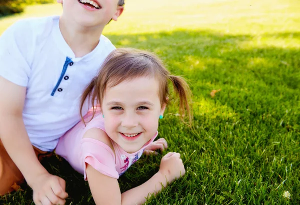快乐的小女孩和她的弟弟躺在草地上 — 图库照片
