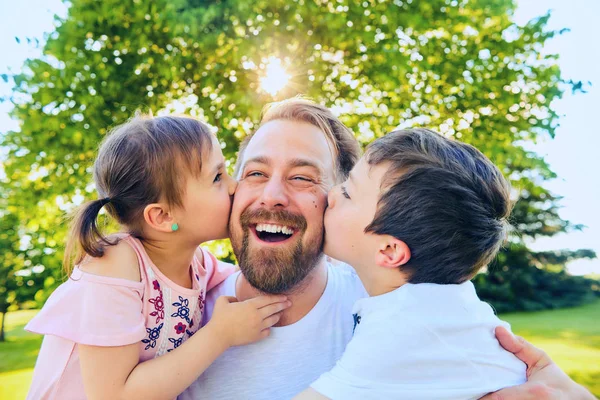 Kleine Jungen und Mädchen küssen ihren glücklichen Vater — Stockfoto