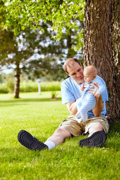 Père souriant jouant avec le fils nouveau-né en plein air — Photo