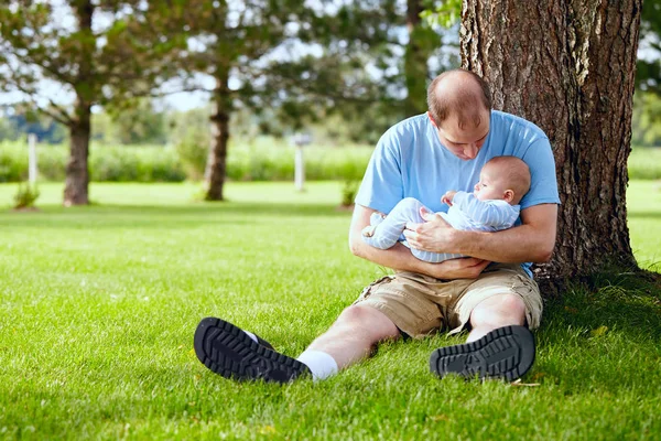 Heureux jeune père berçant son fils nouveau-né en plein air — Photo