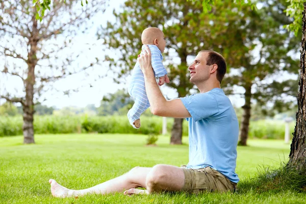 Souriant jeune père tenant le fils nouveau-né en plein air — Photo