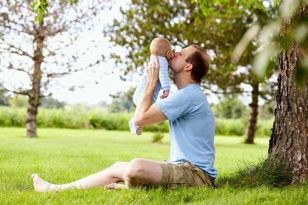 快乐年轻的父亲亲吻在公园的小儿子 — 图库照片