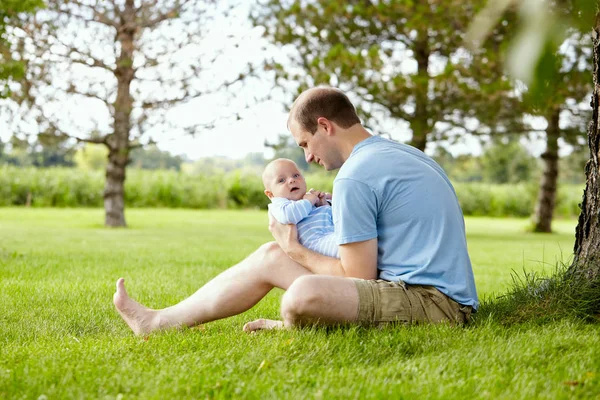 Jeune homme souriant regardant son fils nouveau-né — Photo