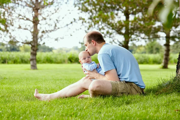 Jeune père embrasser son drôle de fils nouveau-né en plein air — Photo