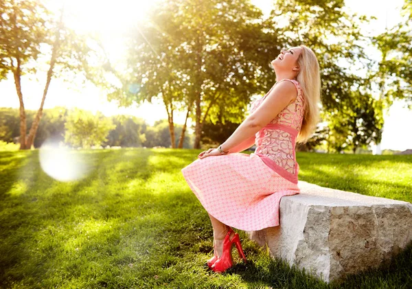 Portrait of happy young woman sitting on stone — Stock Photo, Image