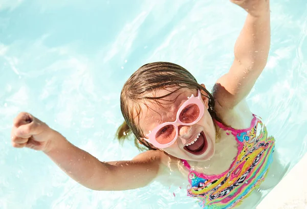 Excited little girl shouting in pool raising arms — Stock Photo, Image