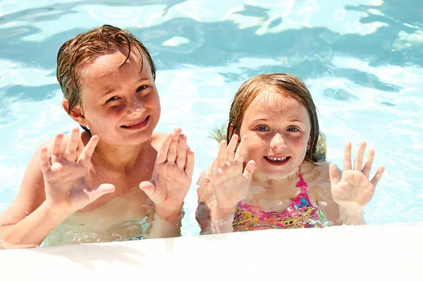 Happy little siblings or friends waving in pool — Stock Photo, Image