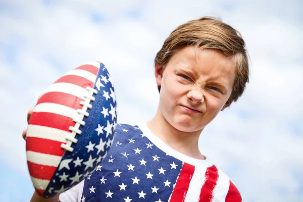 Little American boy holding rugby ball frowning — Stock Photo, Image