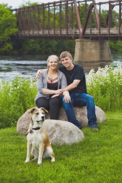 Heureux couple reposant au pont avec leur chien — Photo