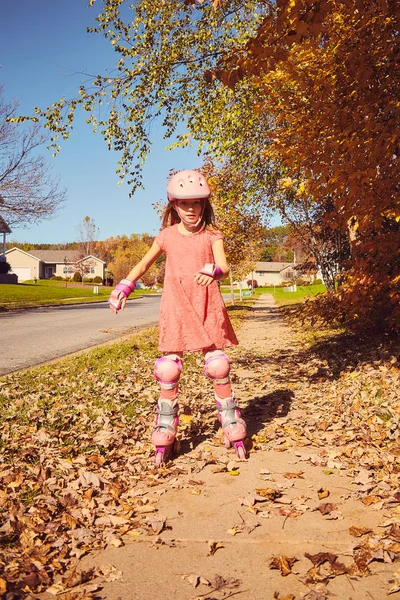 Sorridente pattinaggio a rotelle bambina nel parco autunnale — Foto Stock