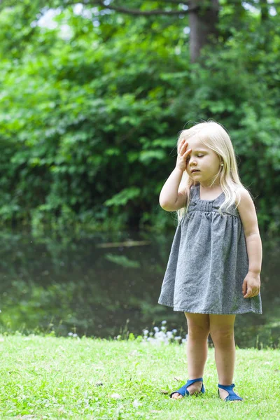 Portrait of sad little girl touching forehead — Stock Photo, Image