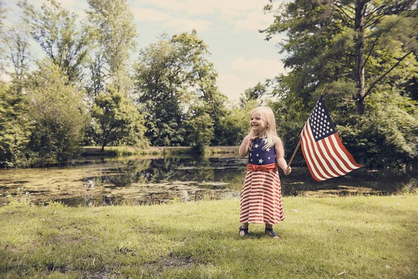 Feliz niña de pie con la bandera de EE.UU. en el parque — Foto de Stock