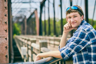 Köprüde duran ve gülümseyen pozitif genç adam