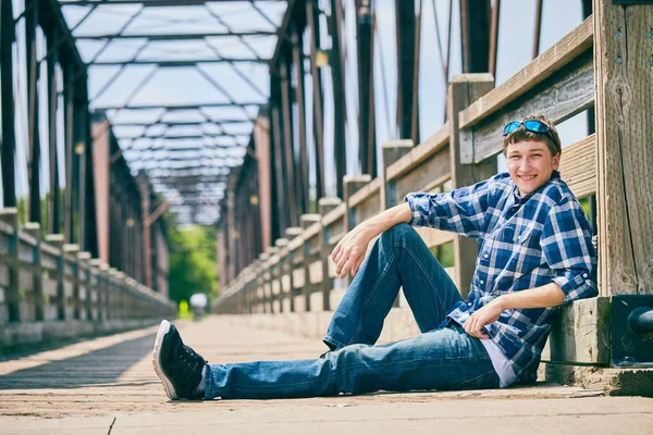 목조 다리에 앉아 행복 한 젊은 사람 — 스톡 사진