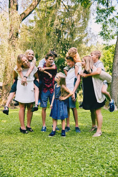 Adolescentes felizes montando piggyback irmãozinhos — Fotografia de Stock