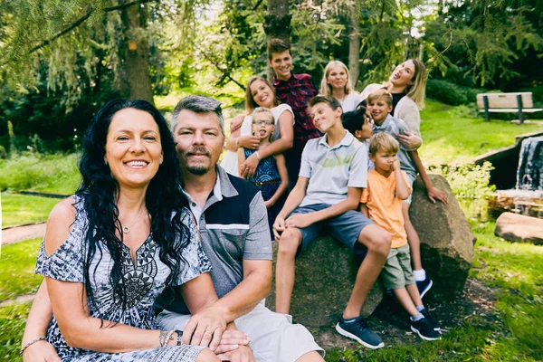 Couple d'âge mûr souriant avec neuf enfants dans le parc — Photo