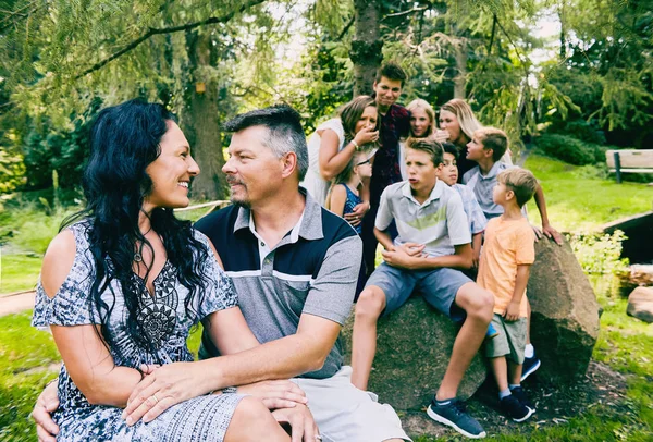 Loving mature couple and nine children in park — Stock Photo, Image